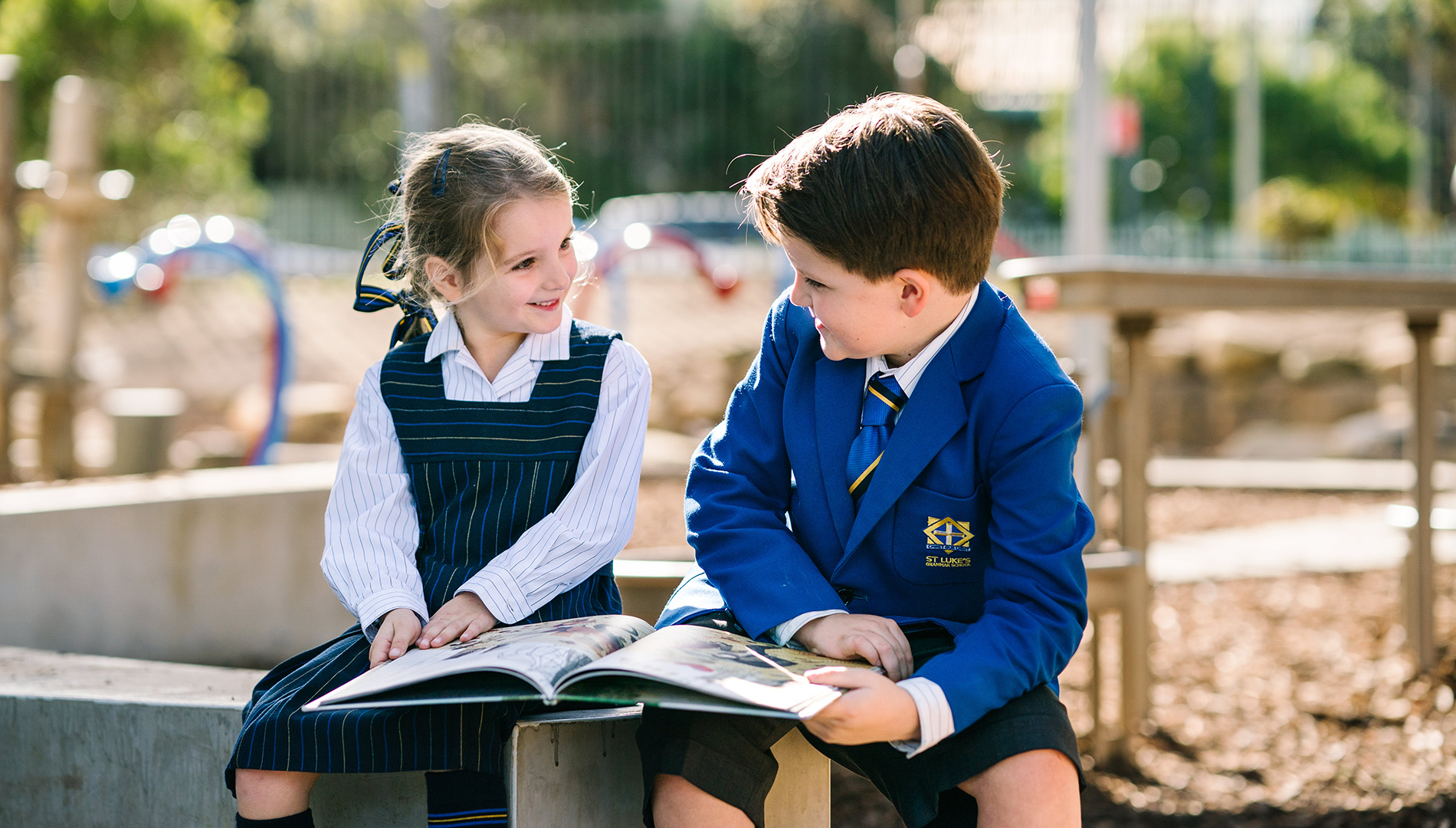 Two students in uniform reading outside